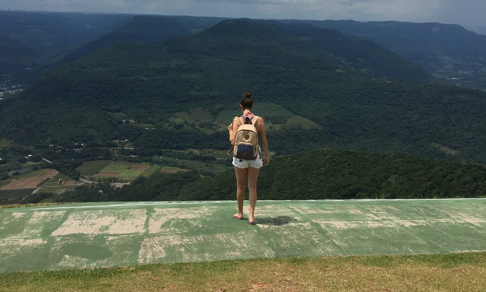 menina de mochila de costas na frente de uma montanha