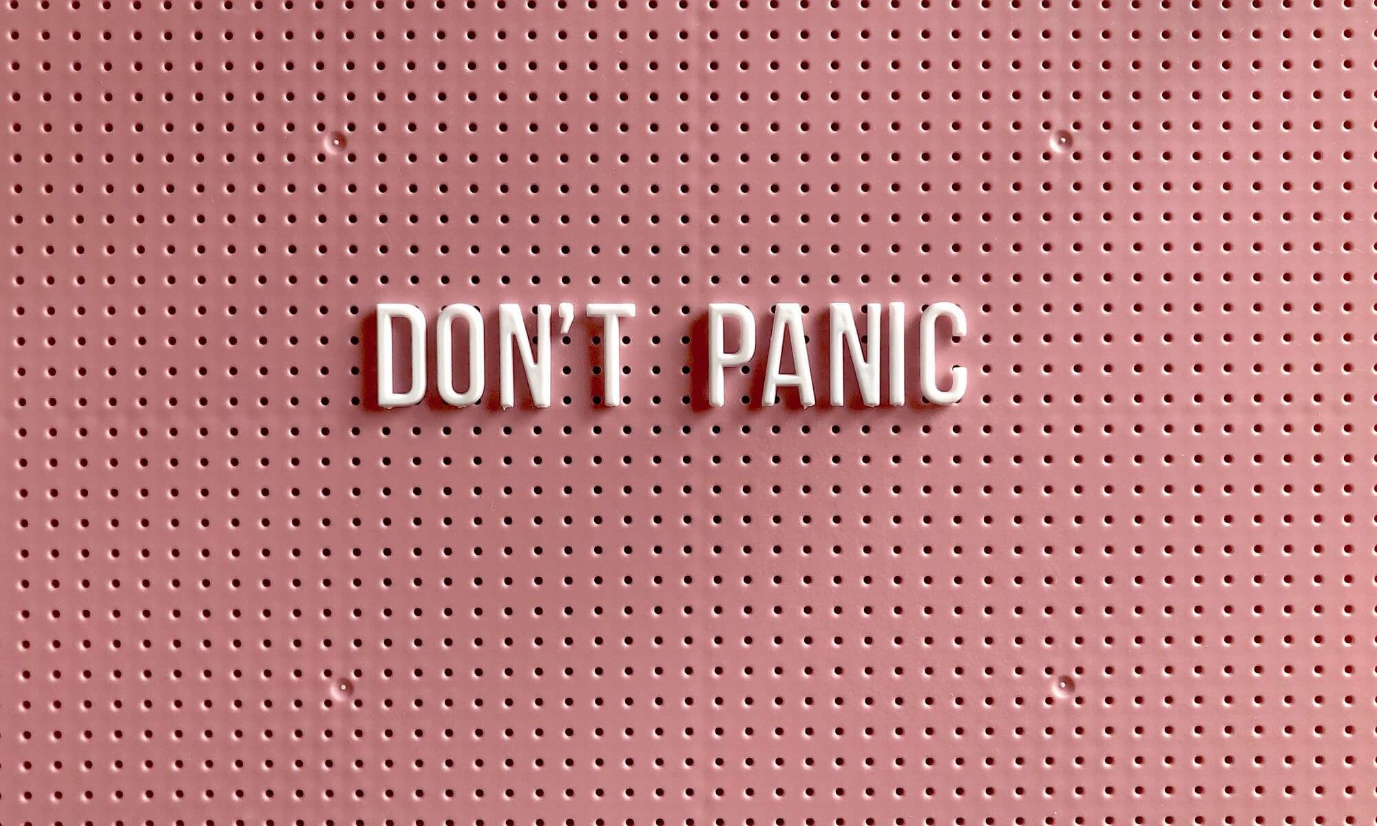 plaquinha de fundo rosa com o texto "don´t panic"
