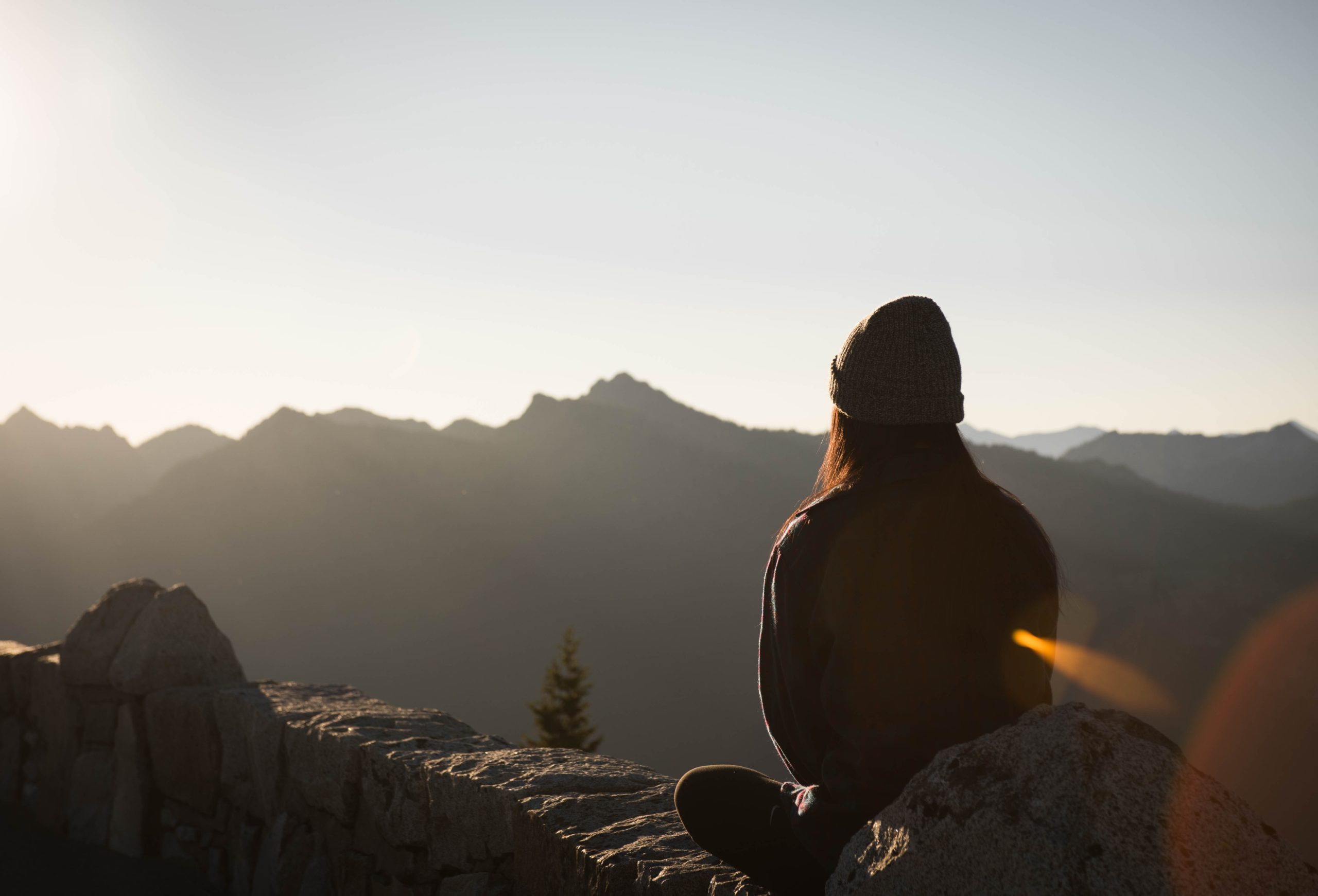 menina de costas com toca de lã olhando as montanhas e meditando