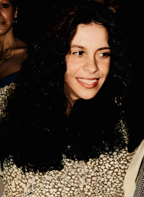 Fotografia da Cantora Gal Costa, na década de 1970, com sorriso aberto, batom avermelhado, cabelos longos, escuros e ondulados. Foto de Domínio Público.