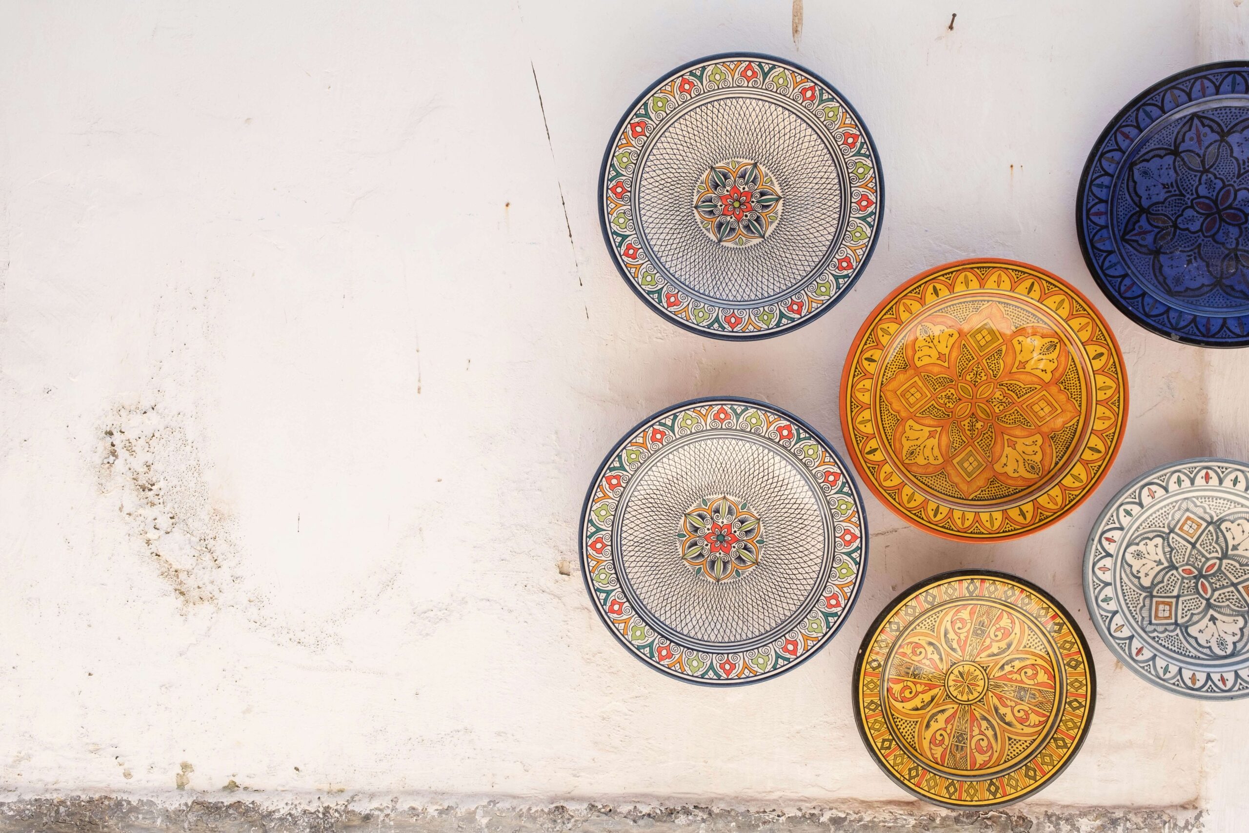 fundo branco com pratos coloridos decorados, em tons de branco e dourado e desenhos de linhas finas - semelhantes a mandalas